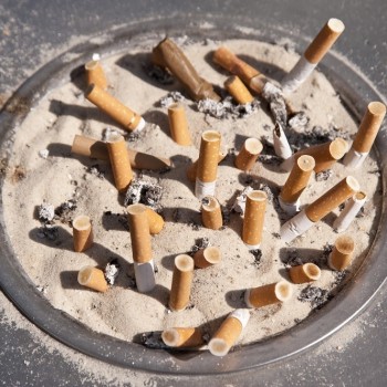 A picture of an ash tray with many spent cigarettes